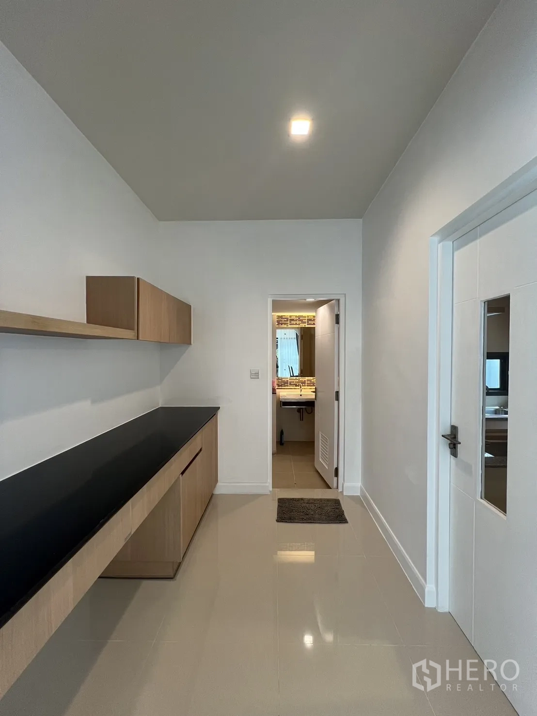 Detached House for rent in Bang Kapi, Bangkok - Pantry with long black countertop and upper cabinets along a white wall.