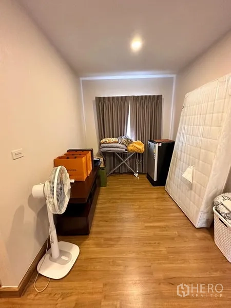 独立式住宅 出售在Prawet, Bangkok - 多功能房间，木地板、遮光窗帘、电风扇与收纳物品。