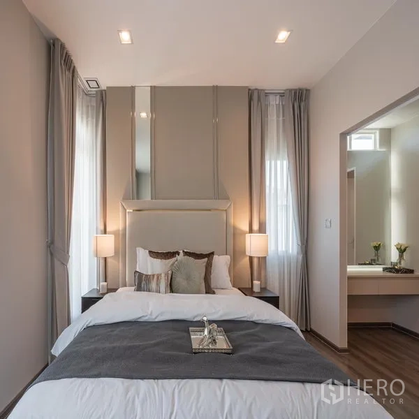 Detached House for rent in Samut Prakan - Master bedroom with large windows, upholstered headboard and soft lighting.