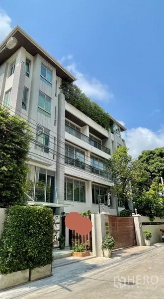 办公空间 出租在Khlong Toei, Bangkok - 现代低层办公楼外观，设有阳台与绿植，入口配安全大门，蓝天下景致。
