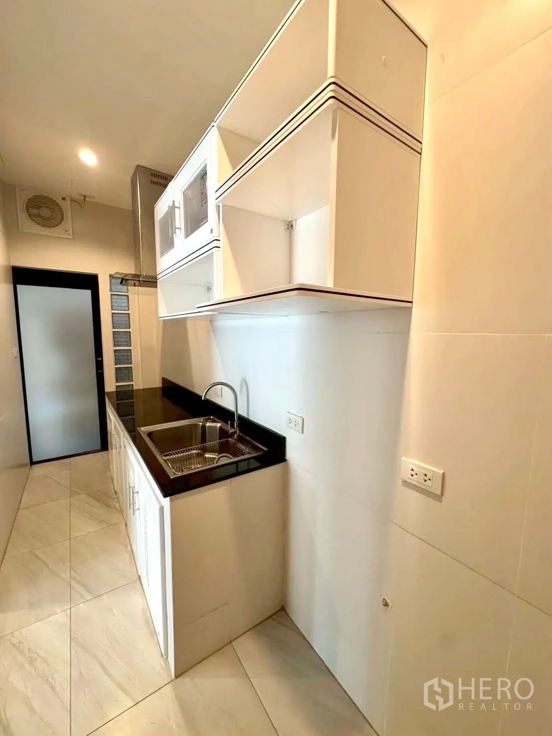 家庭办公室 for rent in Wang Thonglang, Bangkok - 走廊式小厨房，带吊柜、黑色台面与水槽。