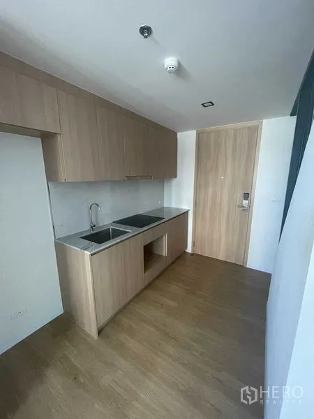 Condominium for rent in Khlong Toei, Bangkok - Compact kitchenette with wood cabinetry, double sink and space for cooktop.