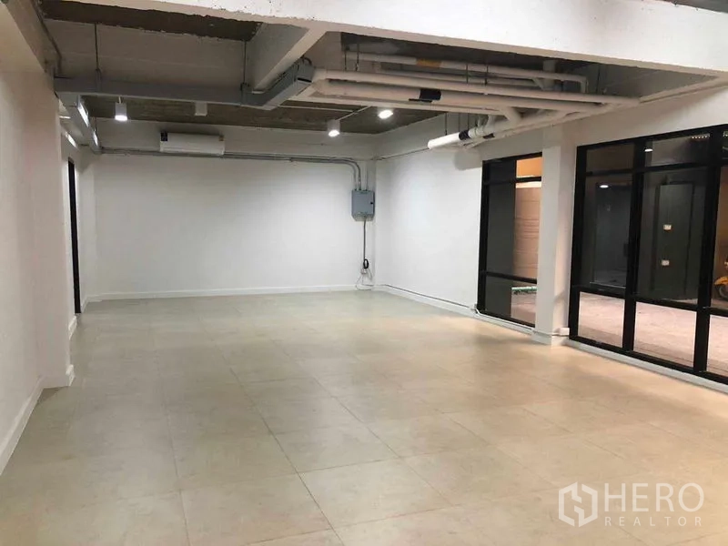 Office Space for rent in Phaya Thai, Bangkok - Spacious office interior with black-framed doors, industrial ceiling and spot lighting.