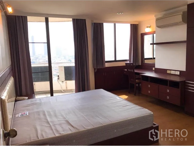 Condominium for rent or sale in Watthana, Bangkok - Master bedroom with large windows, built-in desk and balcony access overlooking the city.