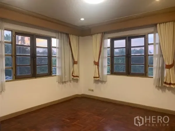 独立式住宅 出租在Khan Na Yao, Bangkok - 采光充足的转角卧室，多扇木框窗与窗帘，拼花木地板。