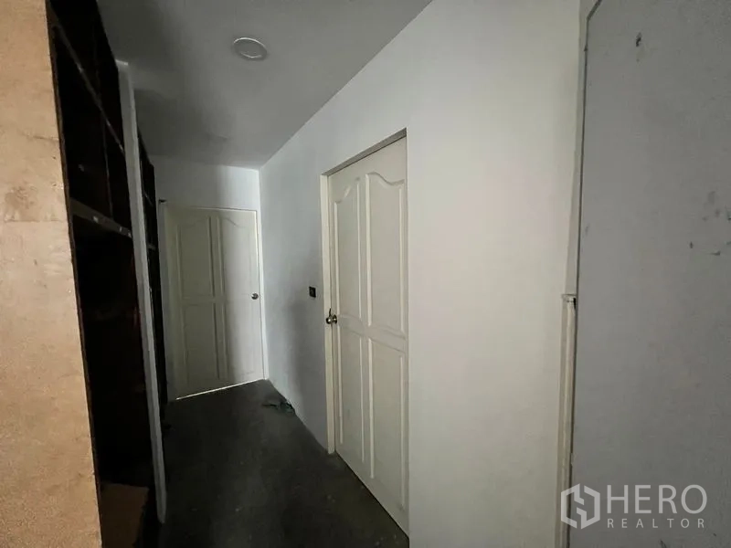Shophouse for rent in Watthana, Bangkok - Interior corridor with white doors leading to service rooms.