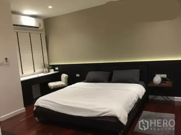 联排别墅 出租在Khlong Toei, Bangkok - 主卧，特大床，窗下内置书桌，深色木地板