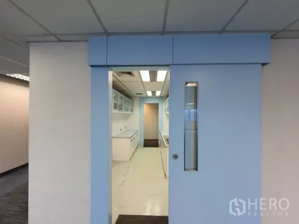 Office Space for rent in Watthana, Bangkok - Sliding door opening to a bright pantry with white built‑in cabinets and fluorescent ceiling lights.