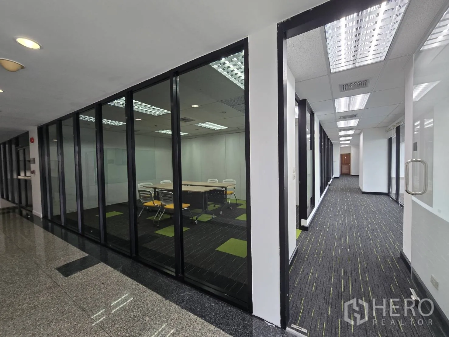 办公室 for rent in Watthana, Bangkok - 玻璃墙会议室与铺有地毯并设天花灯的走廊。