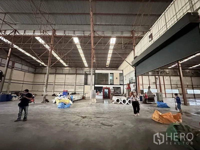 Factory for rent in Bang Bua Thong, Nonthaburi - Wide industrial floor with an internal office block and roller shutter door.