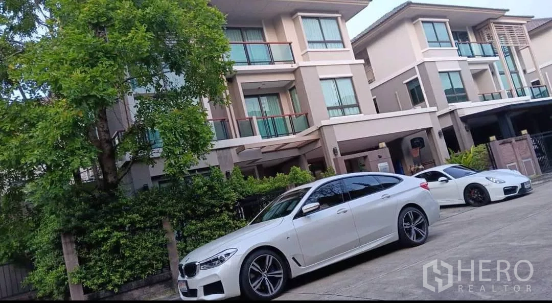 Detached House for rent or sale in Khan Na Yao, Bangkok - Three-storey modern detached house facade with balconies, carport and mature tree.