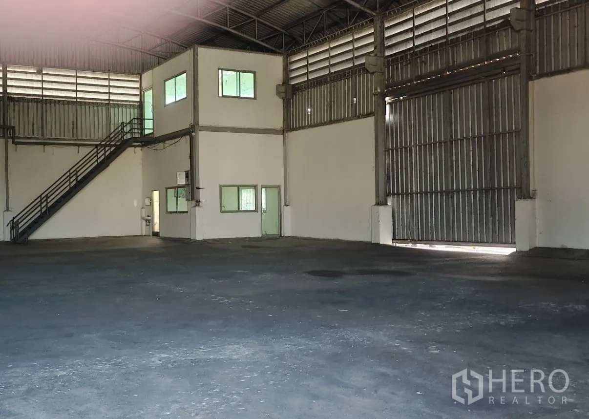 Factory for rent in Lat Lum Kaeo, Pathum Thani - Spacious factory interior with two‑storey office block, metal staircase and large sliding warehouse door.