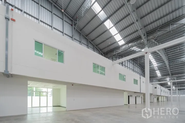 Factory for rent in Khlong Luang, Pathum Thani - Spacious factory hall with high steel roof, skylights, and mezzanine offices with windows.