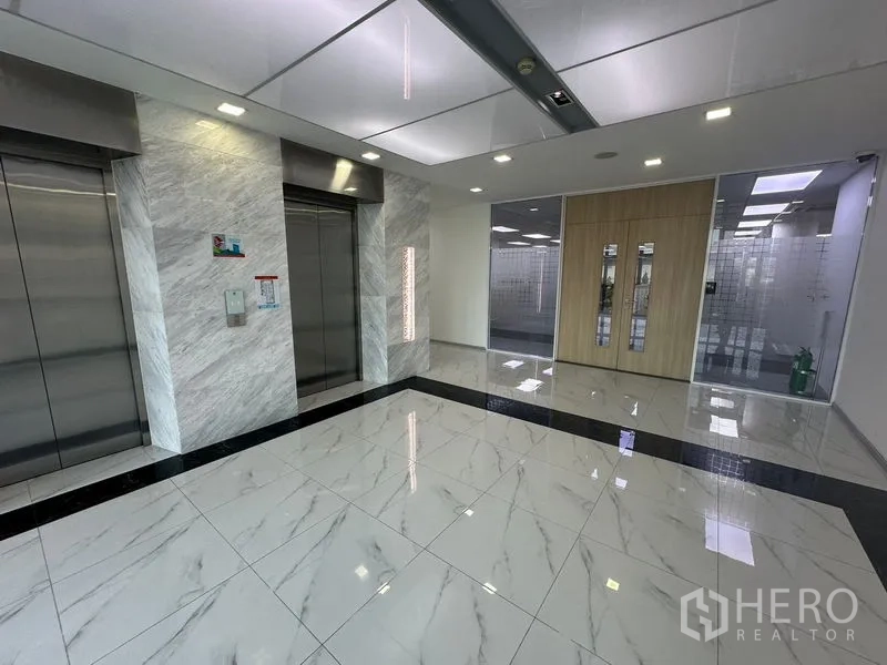 Office Space for rent - Modern elevator lobby with marble-look tiles, two stainless-steel lifts, LED lighting and glass entry to offices.