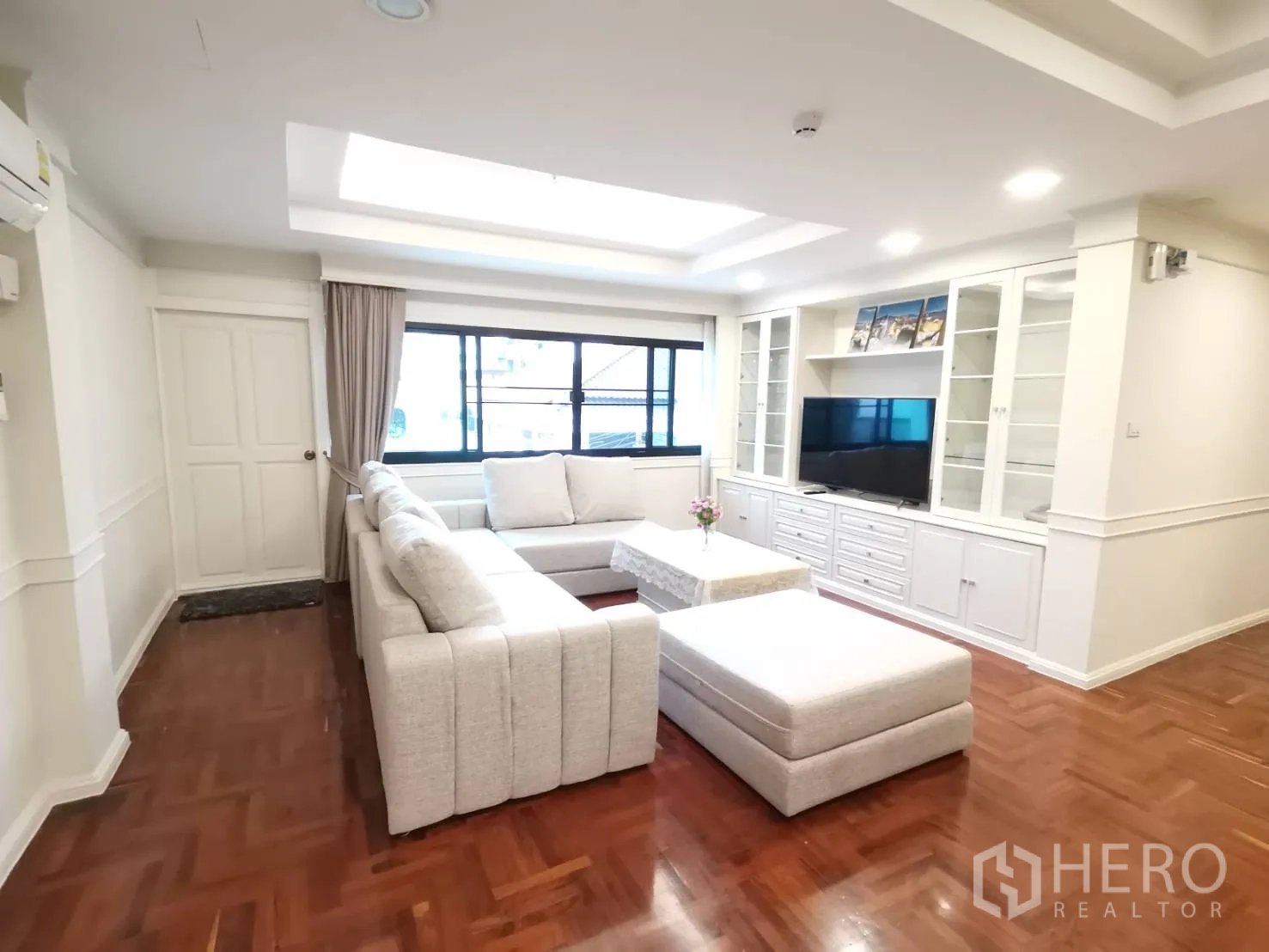 公寓 for rent in Watthana, Bangkok - 舒适客厅，L形沙发、脚凳、内置电视柜与灯带吊顶。