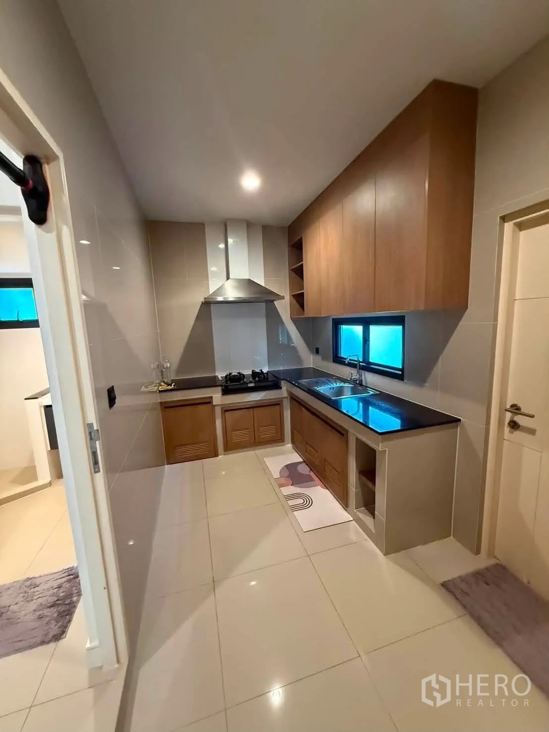 Detached House for rent in Bang Kapi, Bangkok - Separate kitchen with wood cabinets, gas hob, hood, and windows.