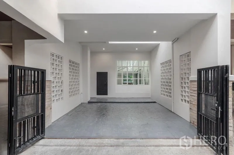 Townhouse for sale - Covered two-car carport with black sliding gates and ceiling downlights.
