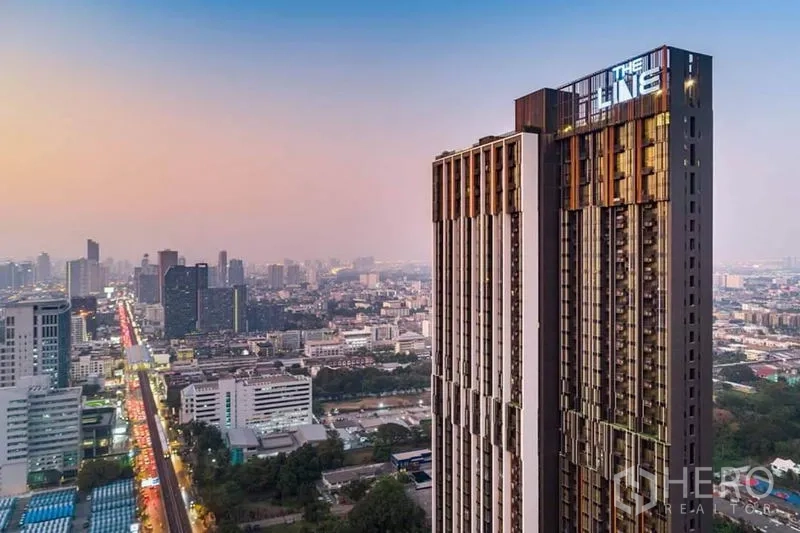 公寓 出租或出售在Phra Khanong, Bangkok - 黄昏时分的 The Line 高层公寓外观，俯瞰曼谷天际线与轻轨。