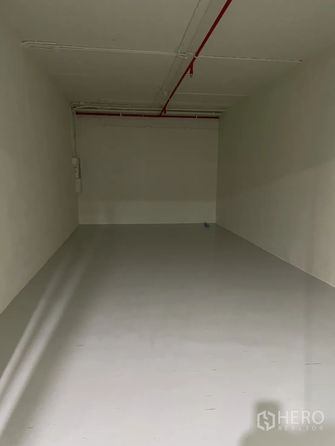 零售空间 for rent in Watthana, Bangkok - 空置长方形铺面，白色墙面、浅色地面，天花有红色消防喷淋管。