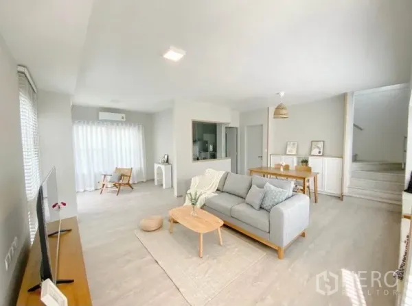 Detached House for rent in Prawet, Bangkok - Open-plan living and dining area with grey sofa, TV console and sheer curtains.