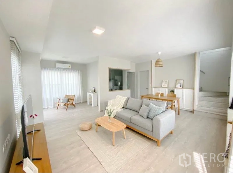 Detached House for rent in Prawet, Bangkok - Open-plan living and dining area with grey sofa, TV console and sheer curtains.