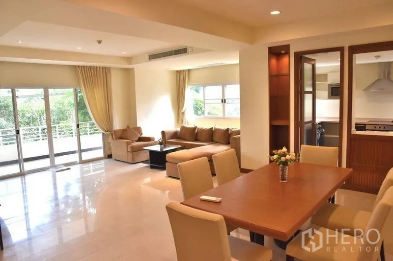 Apartment for rent in Sathon, Bangkok - Bright open‑plan living and dining area with balcony access and neutral decor.