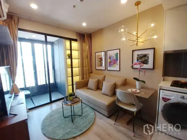 公寓 出租在Huai Khwang, Bangkok - 舒适客厅配沙发与餐桌，现代吊灯，带洗衣机的小厨房，落地推拉门连通阳台。