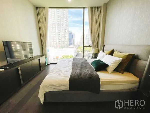 公寓 出租在Watthana, Bangkok - 主卧设大窗与城市景观，电视柜与深色木地板。