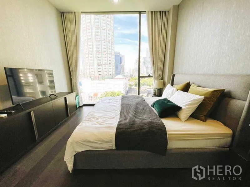 公寓 出租在Watthana, Bangkok - 主卧设大窗与城市景观，电视柜与深色木地板。