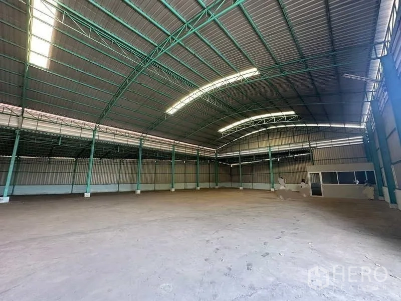 Warehouse for rent in Phra Nakhon Si Ayutthaya - Open storage floor with skylights, steel truss roof, and a corner office enclosure.