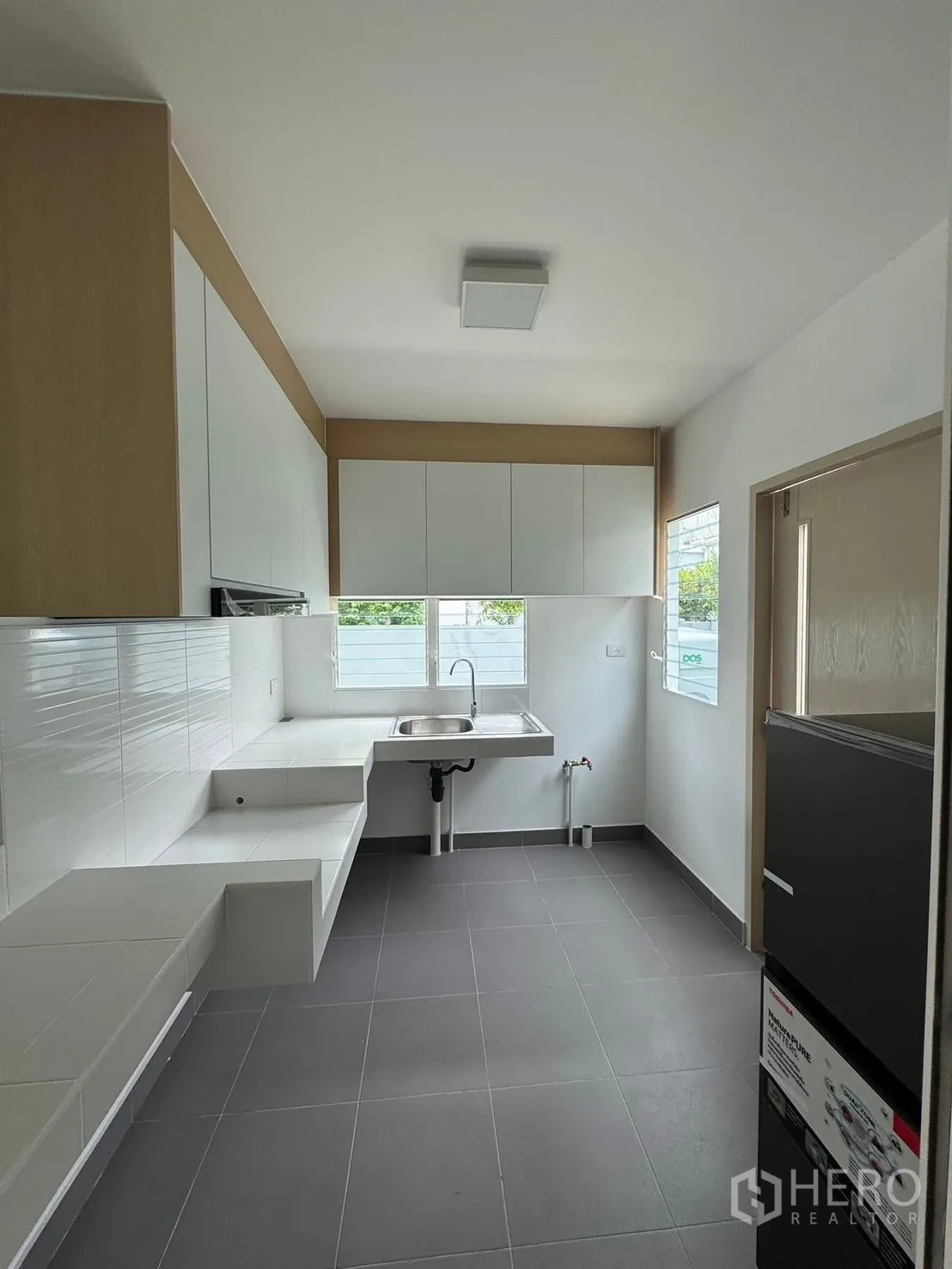 Detached House for rent in Bang Phli, Samut Prakan - Spacious kitchen with grey floor tiles, white cabinetry, and single-bowl sink.