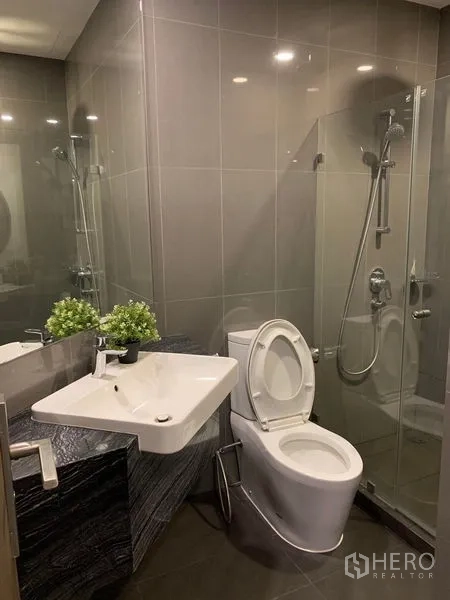 คอนโด ให้เช่าในBang Rak, Bangkok - ห้องน้ำสมัยใหม่ ฝักบัวกระจก อ่างล้างหน้าแขวนผนัง และกระเบื้องโทนเทา