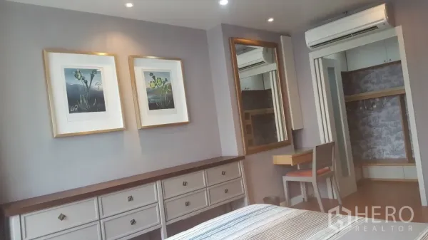 Condominium for rent in Khlong Toei, Bangkok - Wall with framed art, large mirror, dresser and entry to a walk-in closet.