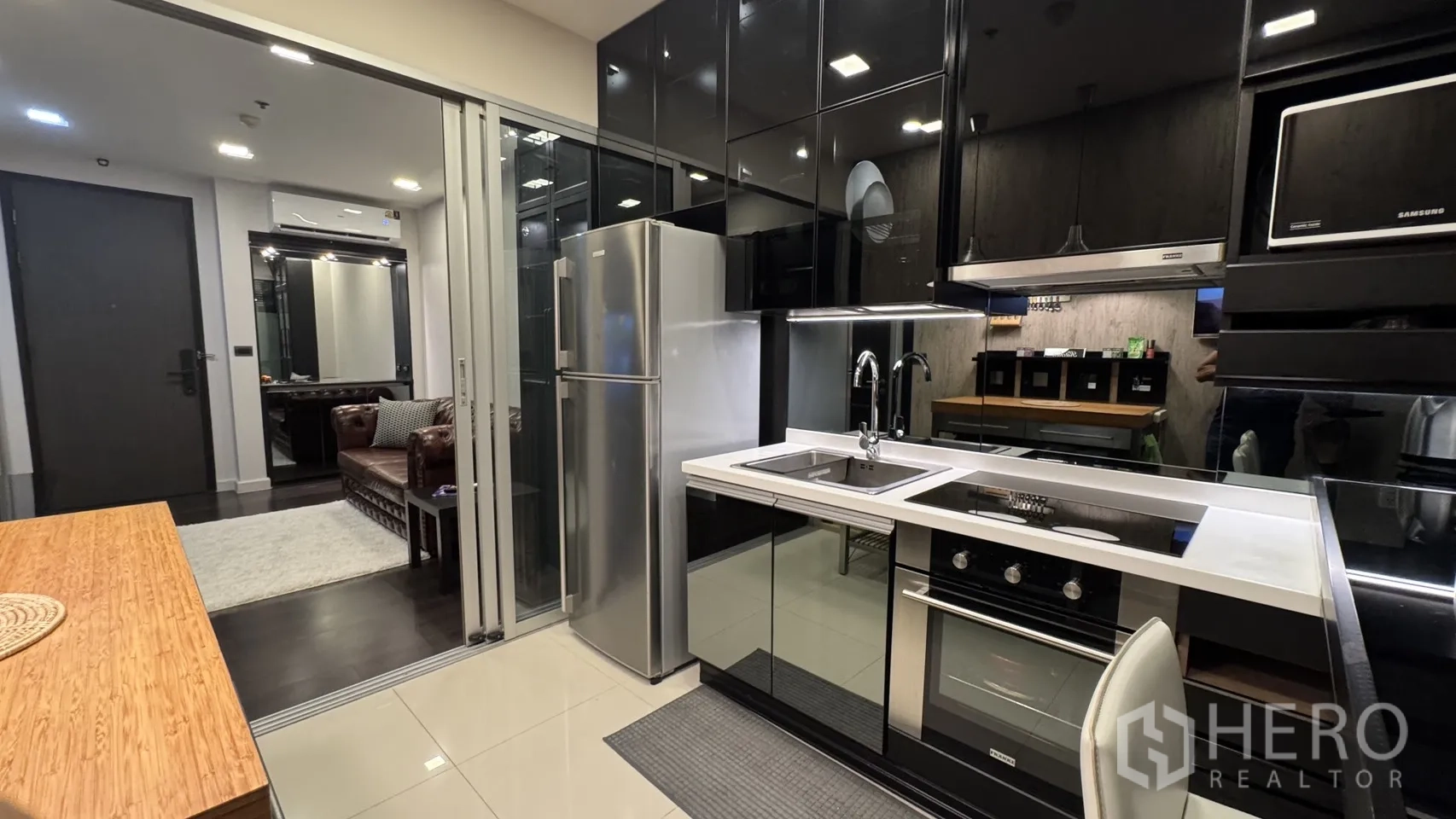 Condominium for rent or sale in Khlong Toei, Bangkok - View from the kitchen toward the living room showing double sink, built-in oven and sliding partitions.