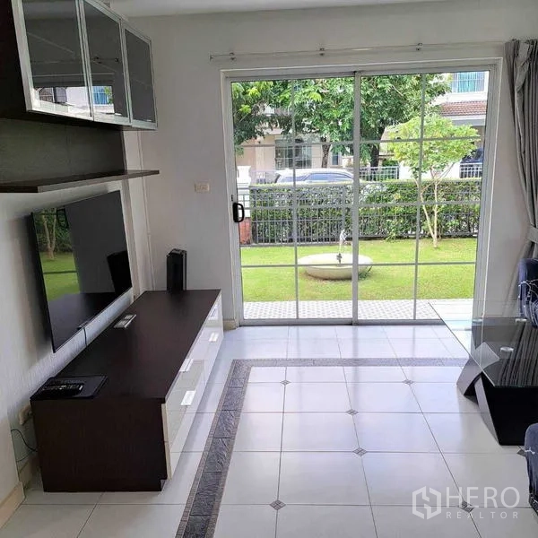 独立式住宅 出租在Prawet, Bangkok - 客厅配电视柜，宽大的推拉玻璃门直通花园。