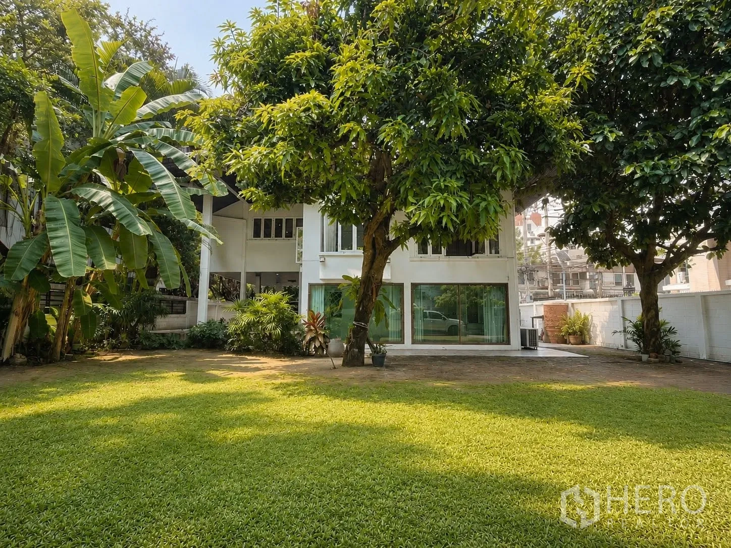Detached House for rent in Pathum Wan, Bangkok - Rear facade of the house with an expansive private lawn and mature trees.