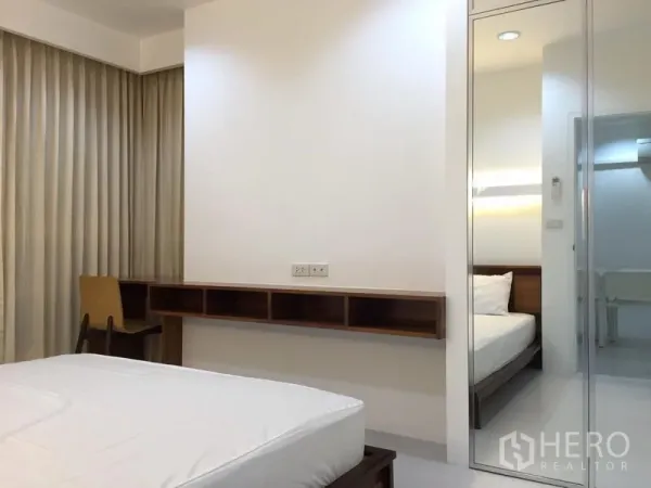 公寓 出租在Bang Rak, Bangkok - 明亮卧室，配书桌、落地窗帘和镜面衣柜。