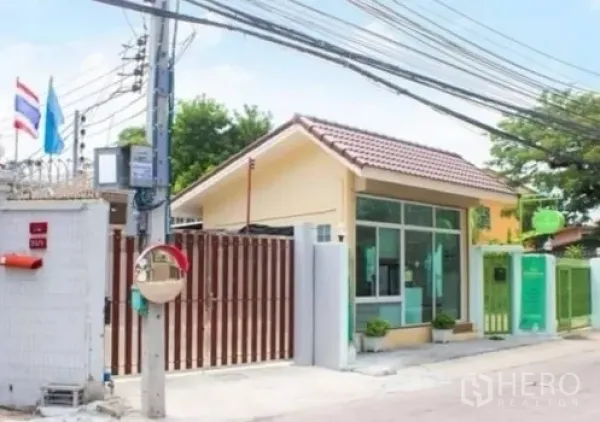 Townhouse for rent in Khlong Toei, Bangkok - Gated neighborhood entrance and guardhouse on a quiet city lane.