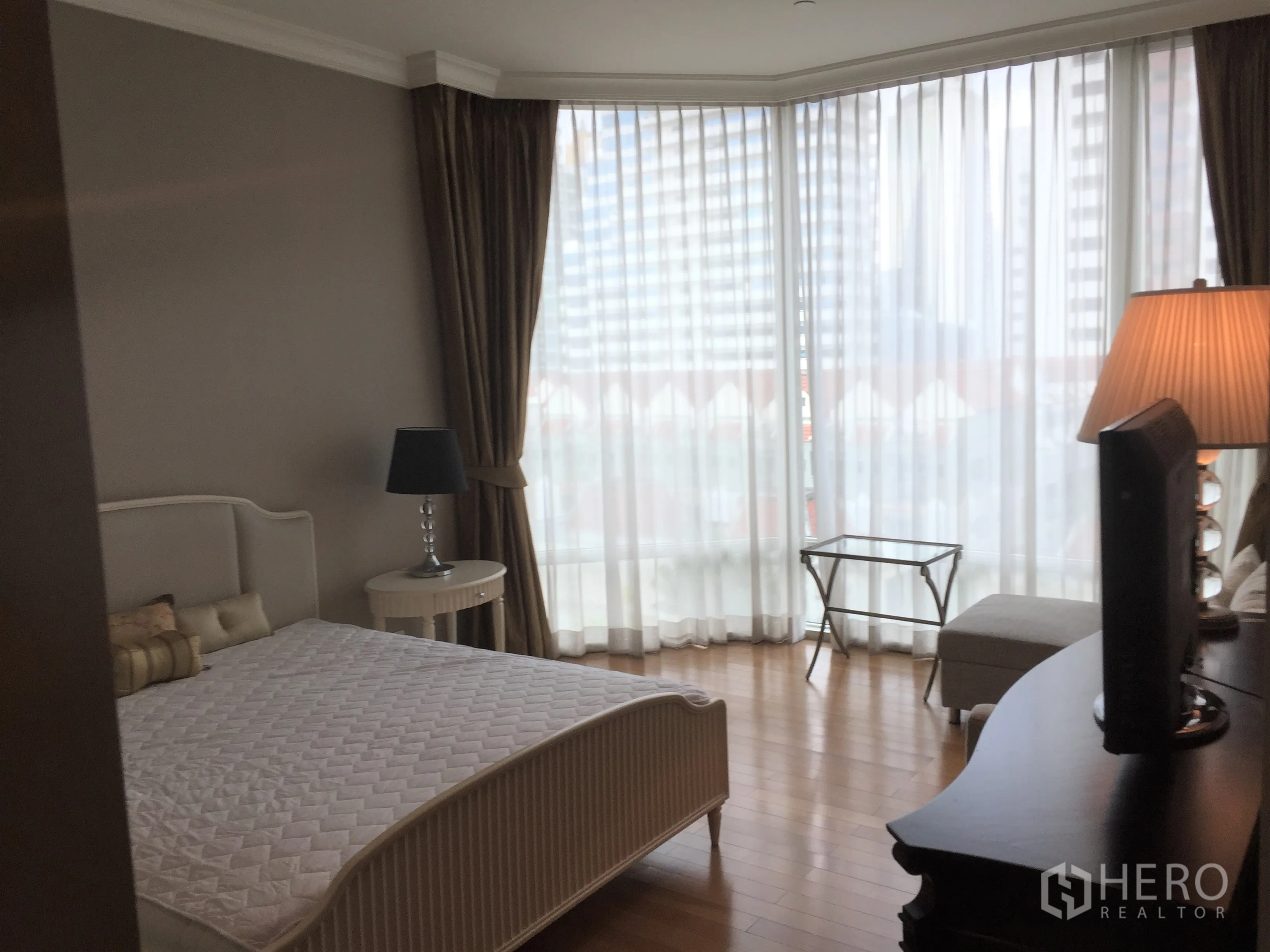 Condominium for rent in Watthana, Bangkok - Spacious bedroom with bay windows, bedside tables and wood flooring.
