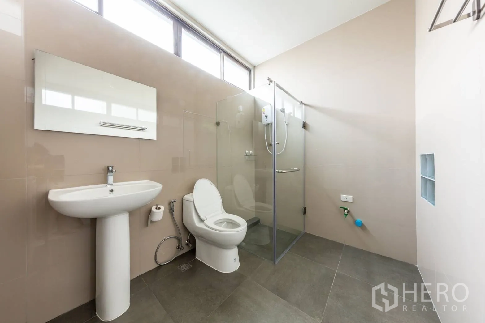 Home Office for rent in Bang Rak, Bangkok - Bright bathroom with high windows, glass shower and neutral tiles.