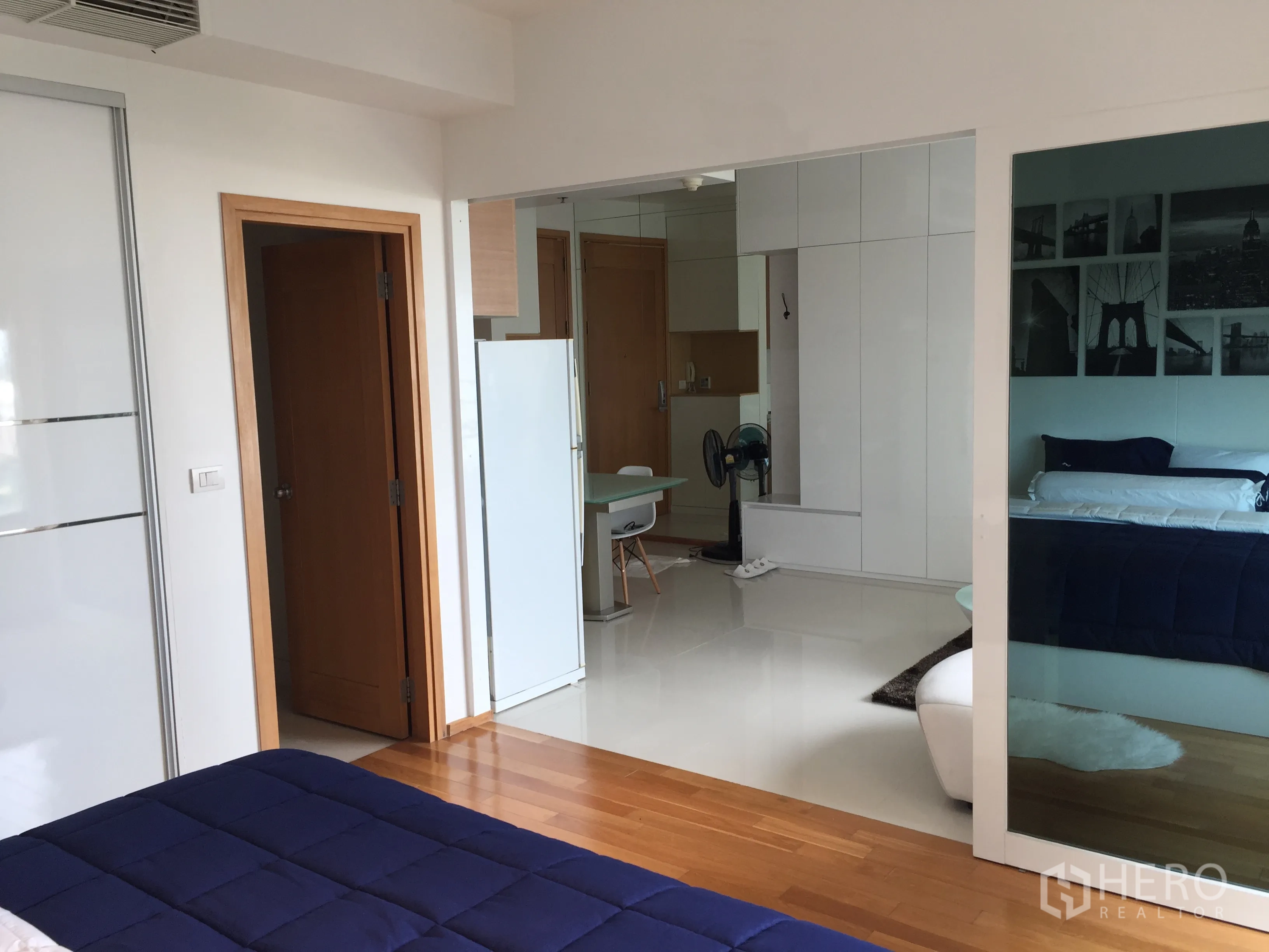 公寓 出租在Khlong Toei, Bangkok - 从卧室望向客厅的视角，带滑动玻璃隔断、木地板与内置收纳。