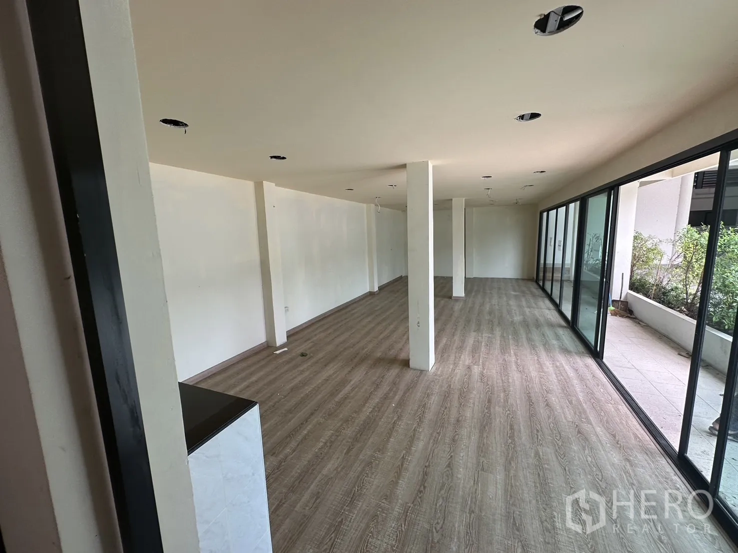 Warehouse for rent in Suan Luang, Bangkok - Ground-floor showroom or office with floor-to-ceiling glass facing planting beds.