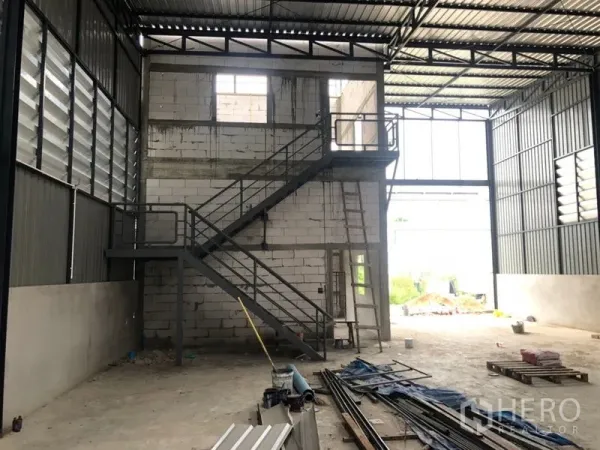 Warehouse for rent in Lam Luk Ka, Pathum Thani - High-ceiling warehouse interior showing stairwell, mezzanine area, and skylight panels.
