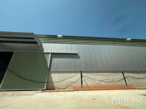Warehouse for rent in Lat Krabang, Bangkok - Corrugated metal warehouse exterior wall with paved loading apron and utility conduits.