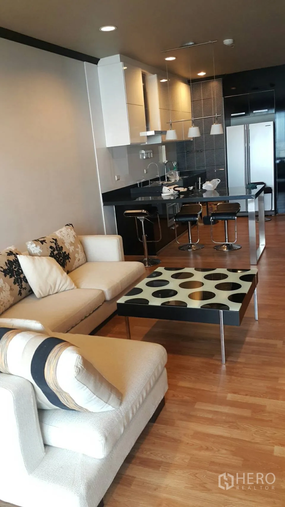 公寓 出租在Ratchathewi, Bangkok - 开放式客餐厨，米色沙发、图案茶几与岛台厨房。