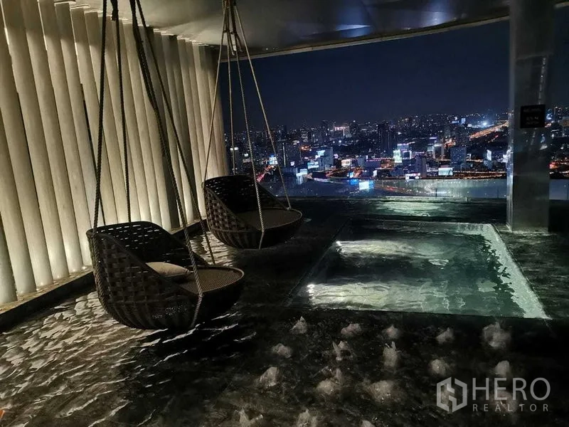 Condominium for rent in Ratchathewi, Bangkok - Hanging basket chairs over a water feature with panoramic night skyline.
