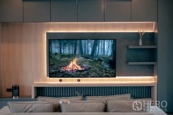 Detached House for rent or sale in Bang Phli, Samut Prakan - Living room feature wall with large TV, wood panels and warm backlit shelving.
