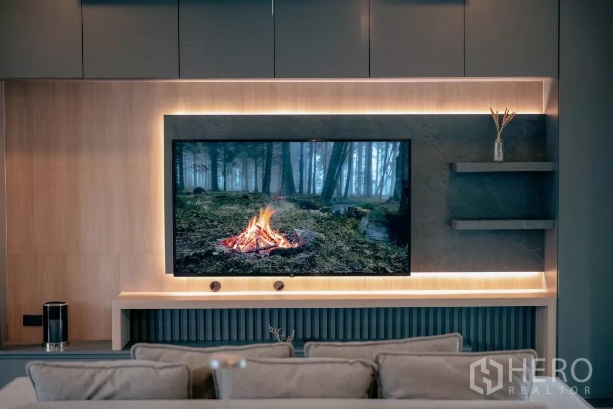 Detached House for rent or sale in Bang Phli, Samut Prakan - Living room feature wall with large TV, wood panels and warm backlit shelving.