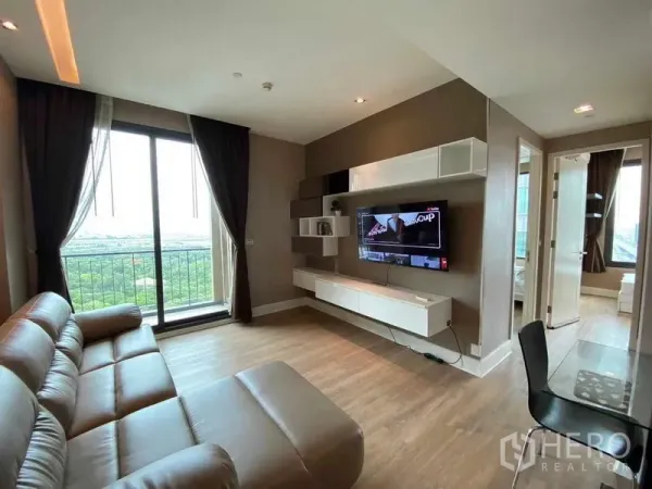 Condominium for rent in Bangkok - Open-plan living and dining area with balcony doors, TV console and park outlook.