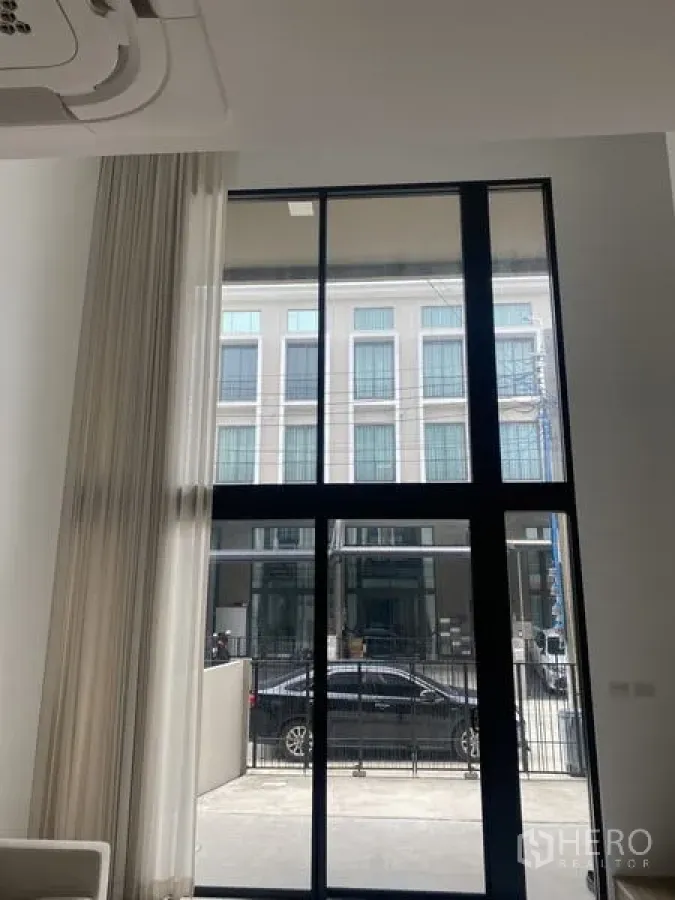 联排别墅 出租或出售在Bang Khae, Bangkok - 采光充足的客厅，黑色框架的落地窗面向街景